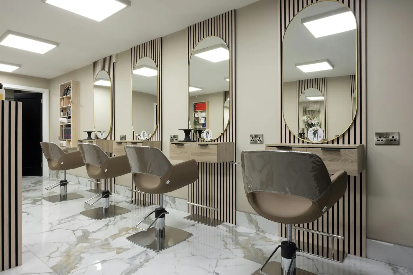 Salon elegant cu oglinzi arcuite și scaune de coafură în nuanțe bej